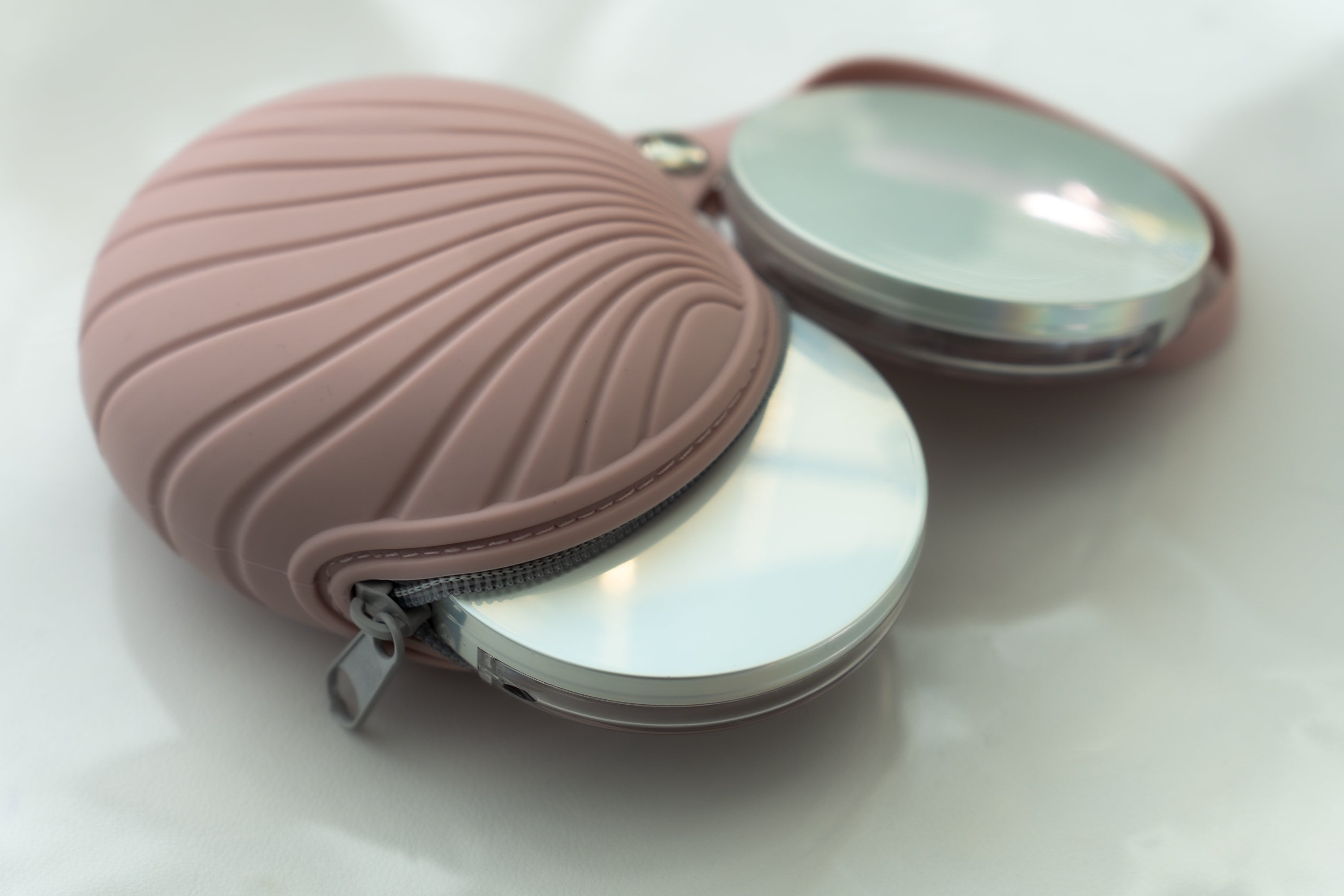 Compact mirror with pink shell-shaped case on a white background